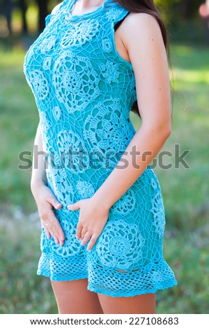 Closeup of a beautiful young caucasian woman posing in an azure handmade knitted dress outdoors