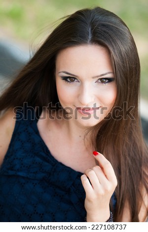 Head shot of a beautiful young woman with long hair looking in camera and touching her hair