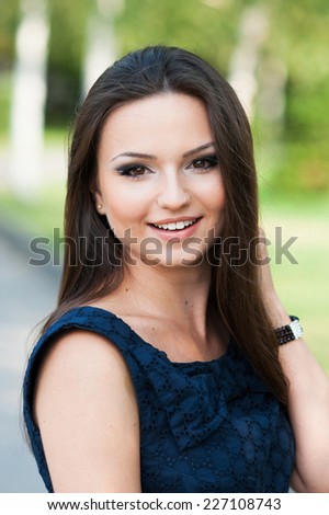 Head shot of a beautiful young woman with long hair smiling and touching hair
