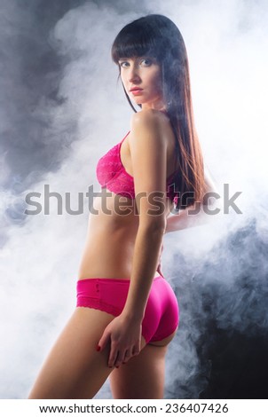 Portrait of a smoking hot sexy fit young woman posing in pink lingerie on dark background