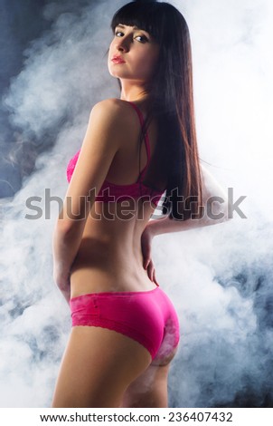 Portrait of a smoking hot sexy fit young woman posing in pink lingerie on dark background