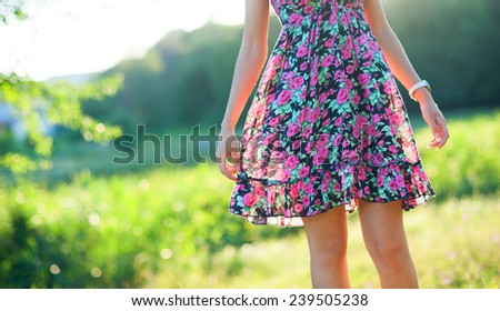 Closeup of happy young woman wearing light summer dress with flowers on sunny day outdoors