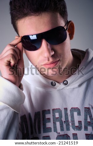 handsome white male holding sunglasses against uniform background