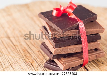 Milk and dark chocolate pyramid on wooden table.