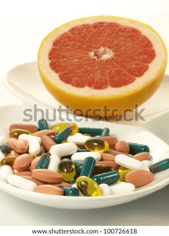 Pills and half of grapefruit on white plate