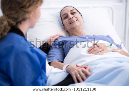 Smiling sick woman enjoying a visit of her caregiver supporting her during chemotherapy