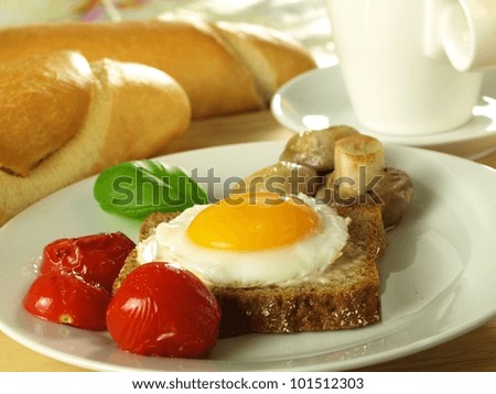 Easter sunny side up egg on a slice of bread with tomatoes with a French loaf.