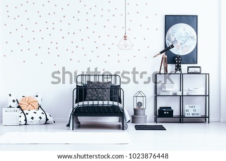 Teenager's bed next to a shelf with telescope against white wall with gold stars and moon poster in bedroom interior