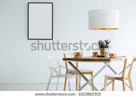 Mockup of empty poster in white dining room interior with lamp above wooden table