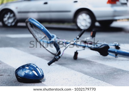 Helmet and bike lying on the road after a car hit a cyclist on a pedestrian crossing