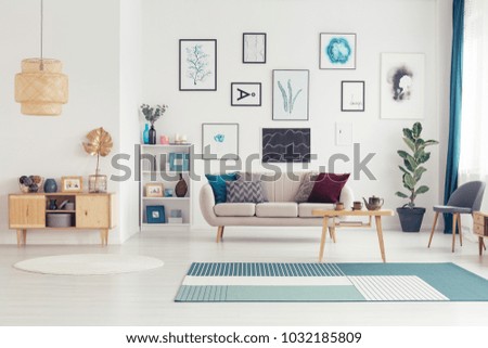 Gold leaf on wooden cupboard in spacious living room interior with table on blue carpet near settee