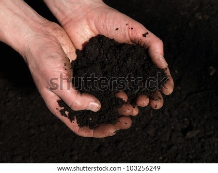 Black moist soil in man\'s hands, closeup