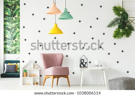 Interior of playroom with pink armchair, colorful chandeliers and wall decorated with stickers
