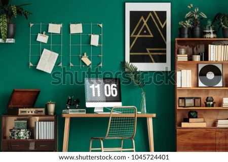 Green home office interior with a computer on the desk, wooden cabinet and poster on the wall