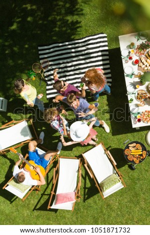 High angle photo of young friends chilling and dancing outdoors at backyard barbecue and grill party, young man playing guitar enjoying sunny holidays with friends