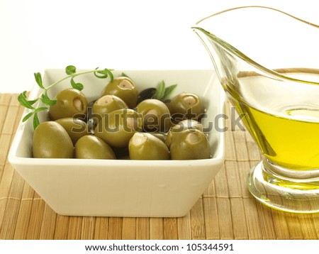 Bowl of green stuffed olives and glass of oil