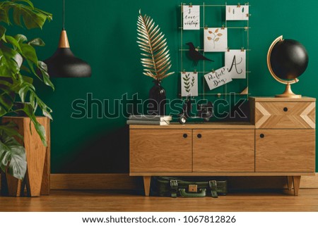 Dark green apartment interior with scandinavian style wooden furniture and designer black and gold decorations