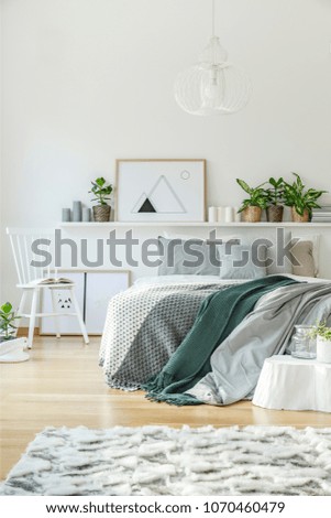 Bedroom interior with king-size bed, rug, chair, ornaments and wooden floor