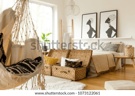 African bedroom interior with a swing, boxes with pillows, double bed and posters