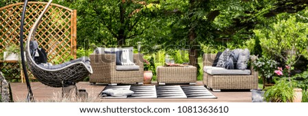 Picnic food and cold lemonade in glass carafe placed on a garden table standing on a terrace with hammock chair