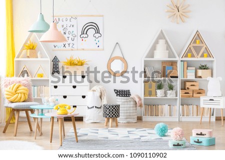 Two simple posters hanging on white wall in kids room interior with material baskets, wooden furniture and pastel lamps