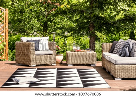 Comfy garden furniture and geometrical rug on a terrace in spa resort
