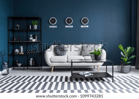 Patterned carpet in navy blue living room interior with black table in front of beige couch