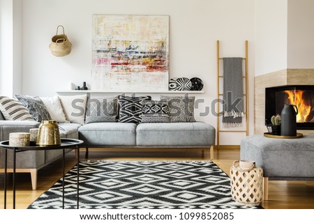 Patterned carpet in decorative living room interior with painting above couch. Real photo