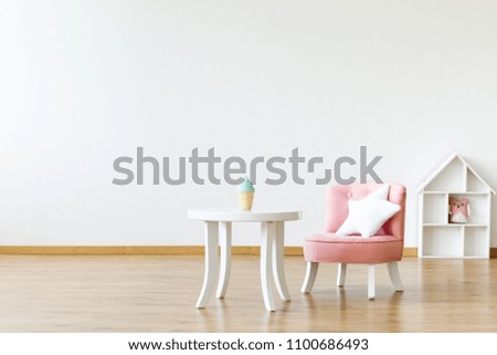 Kid\'s table and chair with a star pillow in a white, empty room interior with a dollhouse in the background. Place for your product