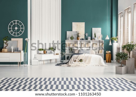Spacious studio apartment interior with turquoise green walls, white double bed and scandinavian furniture