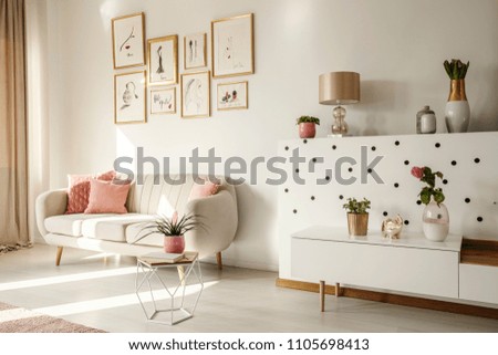 Side angle of a living room interior with white sofa, coffee table, cabinet, art collection and plants