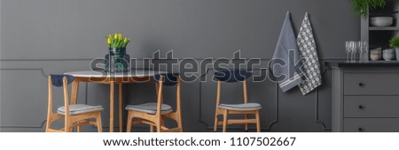 Grey, wooden chairs at round table against grey wall with molding in dining room interior