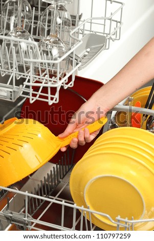 Woman\'s hand putting dirty dishes into dishwasher