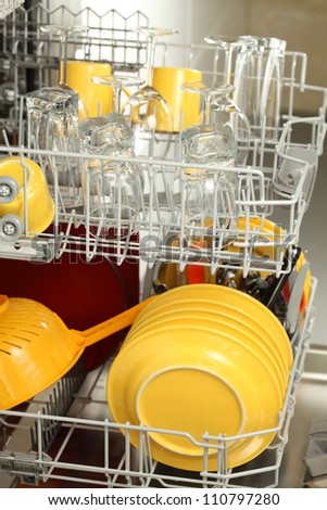 Open dishwasher full of plates and glasses