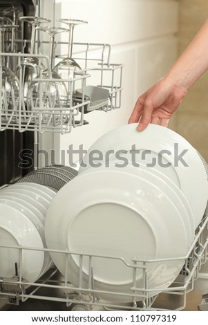 Woman's hand taking clean plate from dishwasher