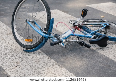 Blue child\'s bicycle lying on a pedestrian crossing after a traffic accident