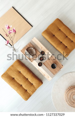 Top view on wooden table with cups between poufs in dining room interior with flowers. Real photo