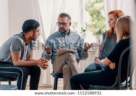 Counselor talking to a group of rebellious teenagers with depression