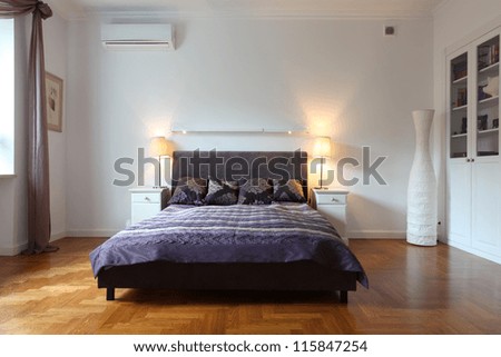 Stylish white bedroom with a purple bed