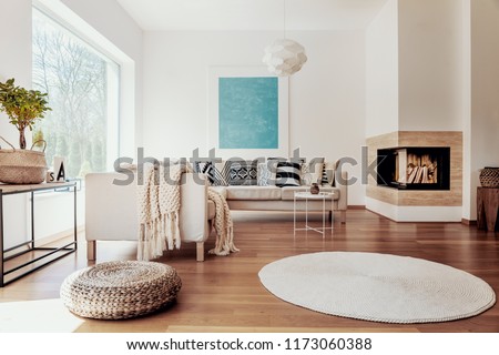 Beige and white textiles and a modern spherical pendant light in a sunny, tranquil living room interior with natural decor.