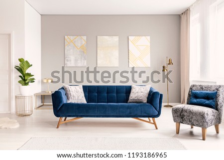 A modern living room interior of a luxurious hotel apartment with a designer couch, an armchair and art decorations. Real photo.