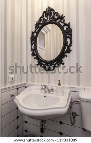 Elegant white sink and oval mirror in toilet