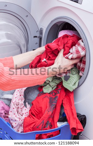 Woman\'s hands putting clothes into washing machine