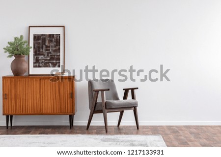 Vintage living room interior with retro furniture and poster on the cabinet, real photo with copy space on the white wall