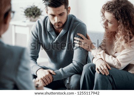 Supportive beautiful wife touching husband\'s arm during psychotherapy session for married couples with problems