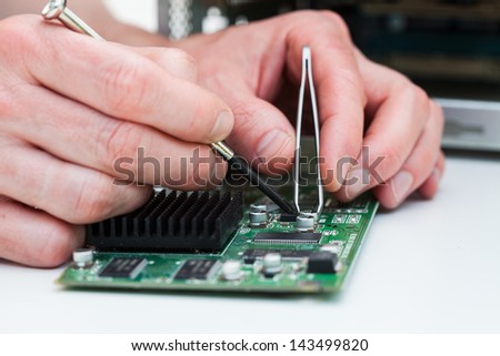 computer specialist use tweezers to repair circuit printed board