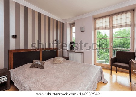 Vintage mansion - a stylish beige bedroom with a bed by a striped wall
