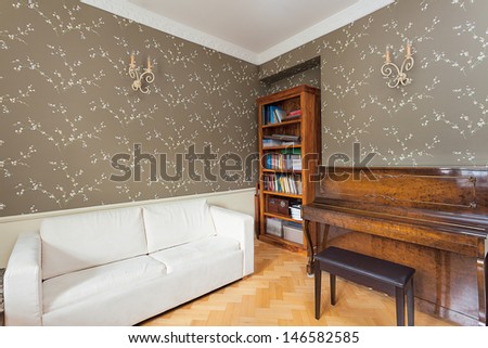 Vintage mansion - a leisure room with a bookshelf, a piano and a white sofa