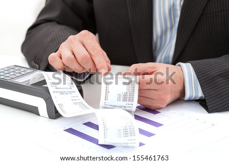 Man\'s hands analysing the expenses and a bar chart
