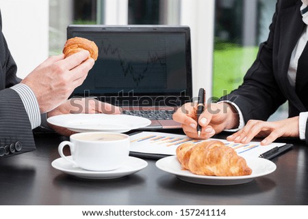 Business people with coffee and croissant during chart analysis